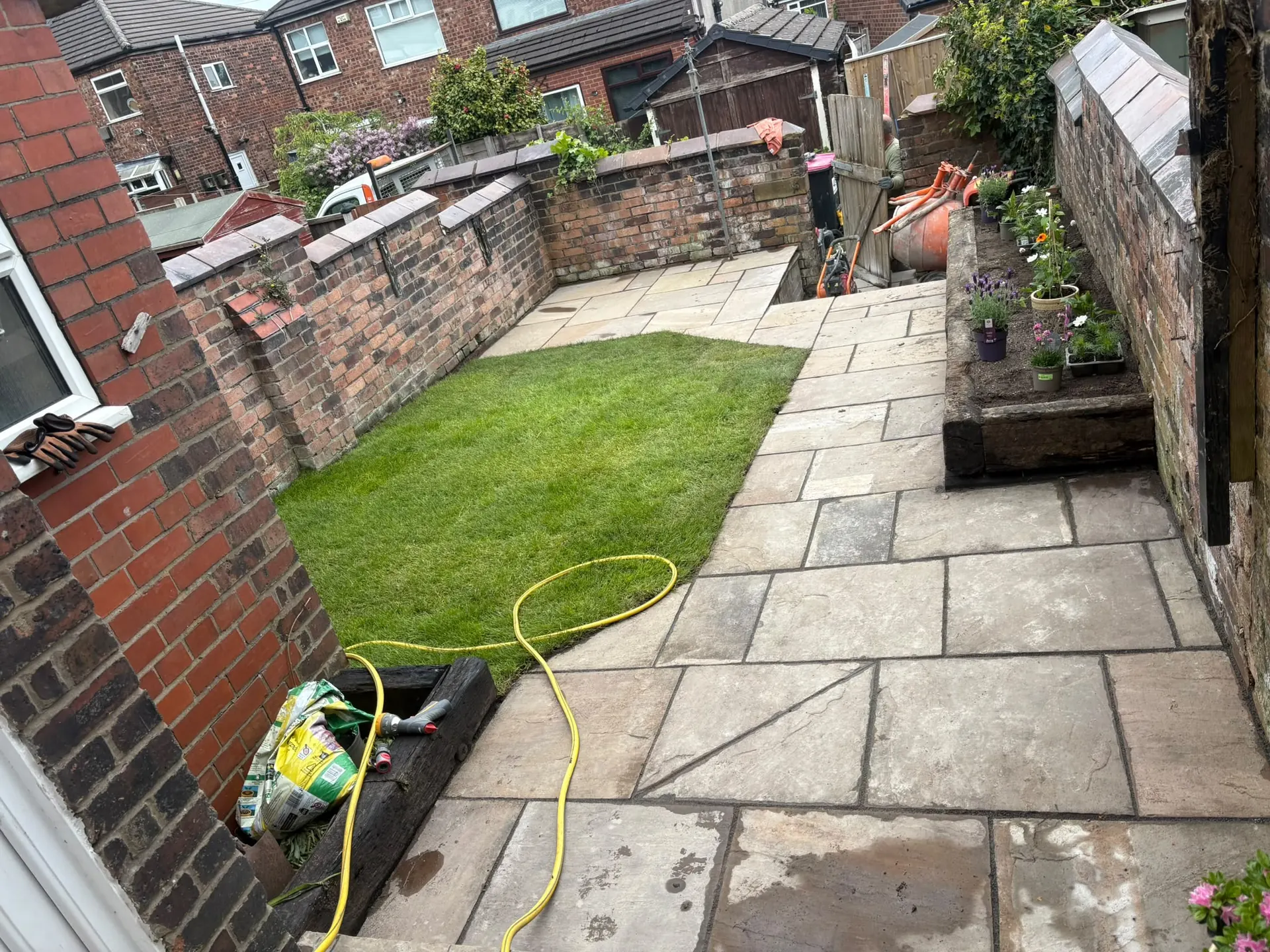 Indian sandstone paving with new turf lawn and a timber sleeper edged planting bed