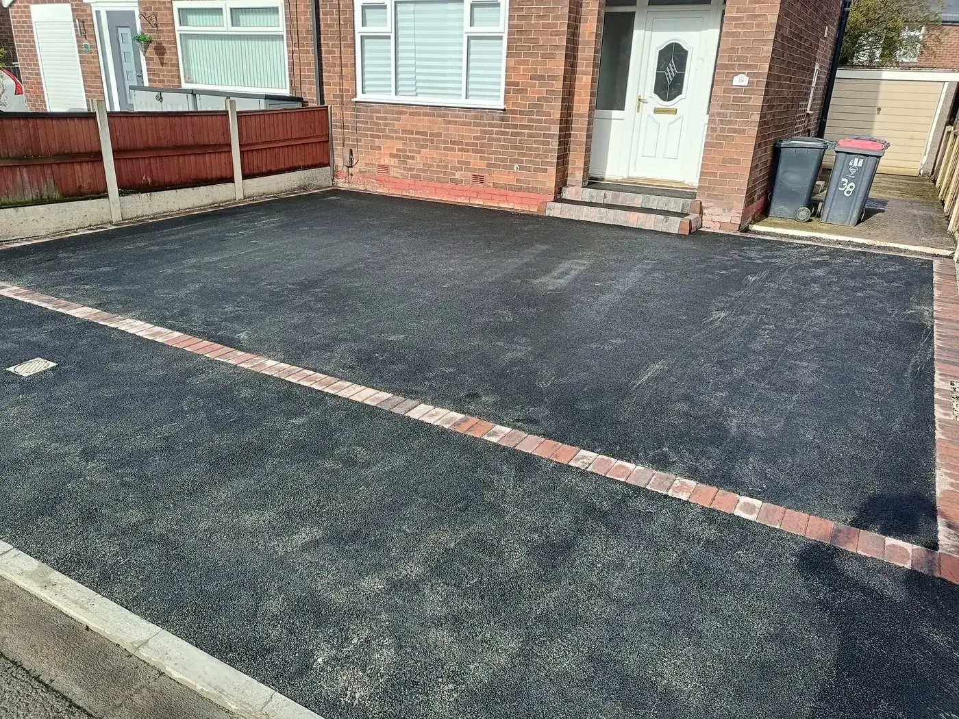 Finished tarmac driveway with red brick banding in front of a red brick semi, laid by DVH Innovations