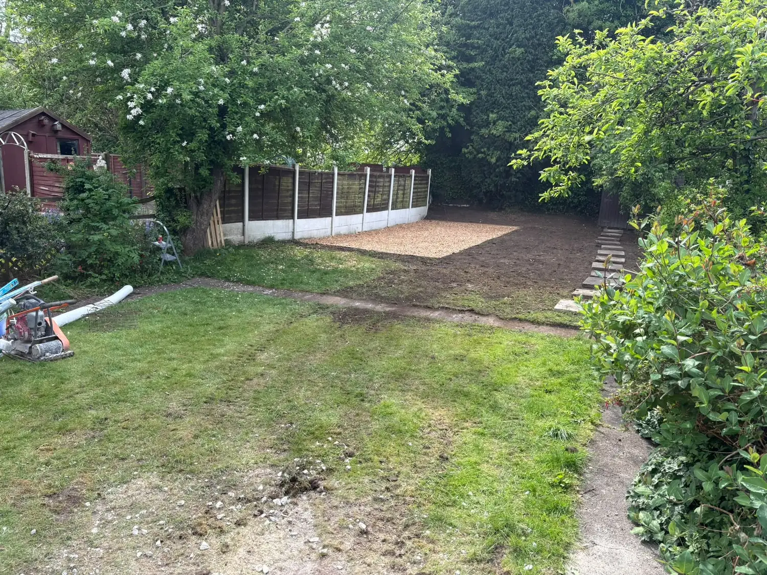 Turf rolls and a bark chip play area set out across prepared soil during landscaping
