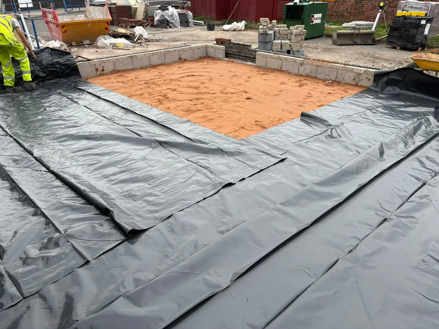 Damp proof membrane laid over sand blinding and lapped up the block perimeter walls