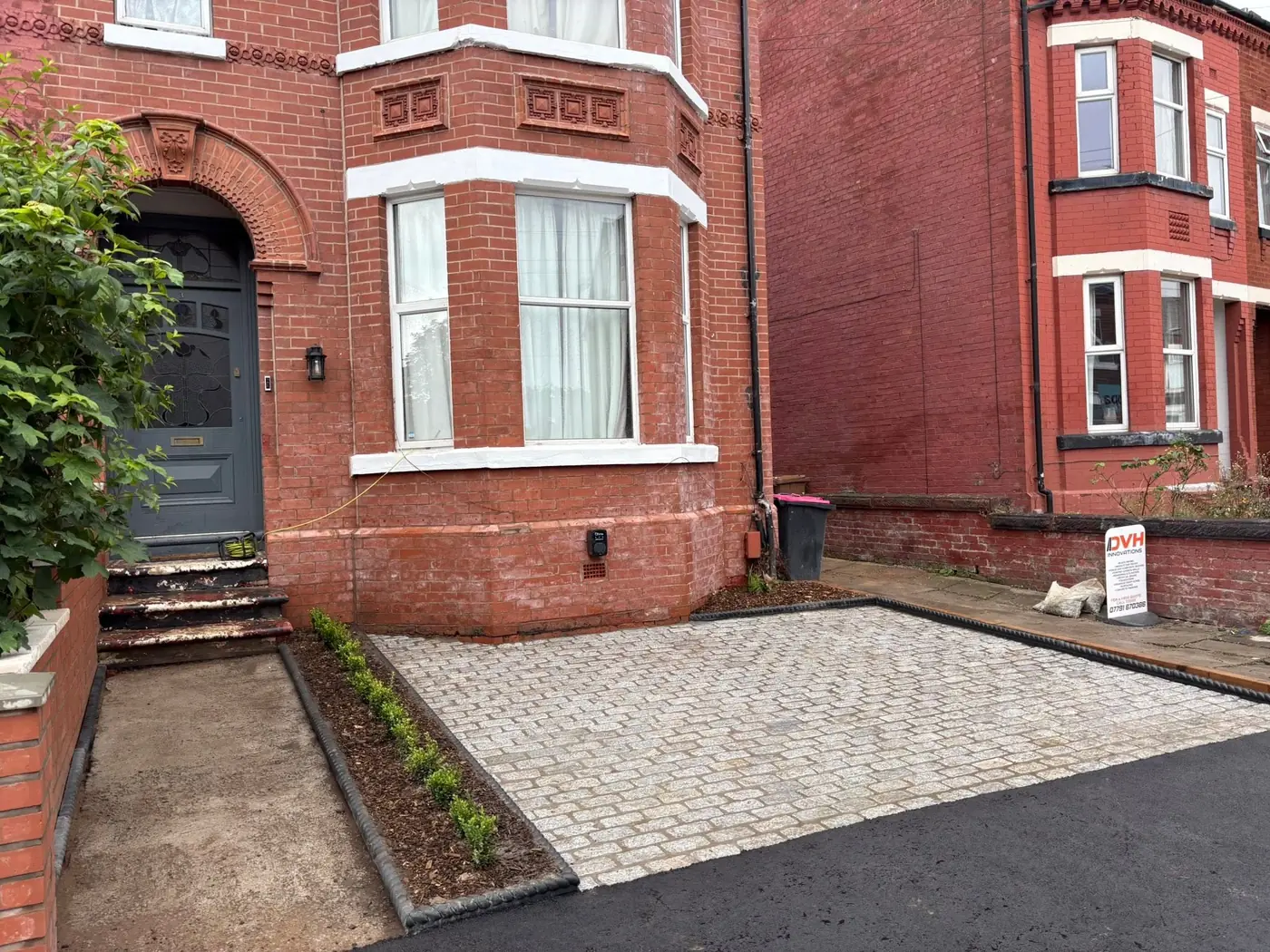 Granite setts driveway with a tarmac apron and new planted border in front of a red brick Victorian semi