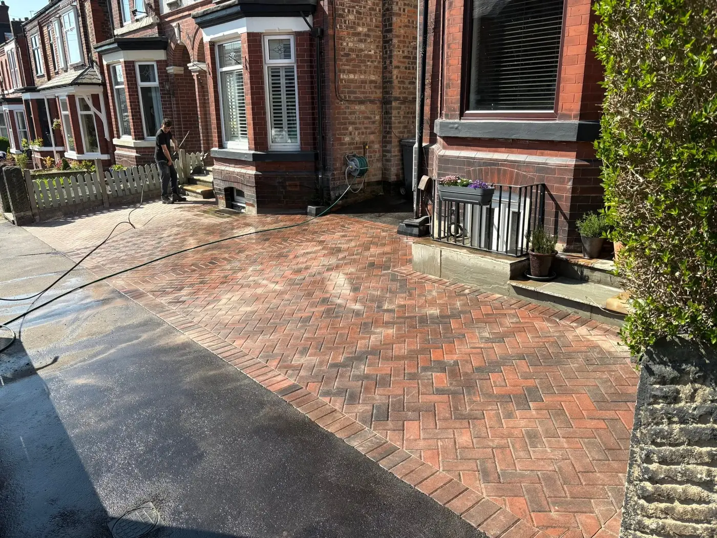 Finished herringbone block paved driveway in full sun outside a red brick terrace